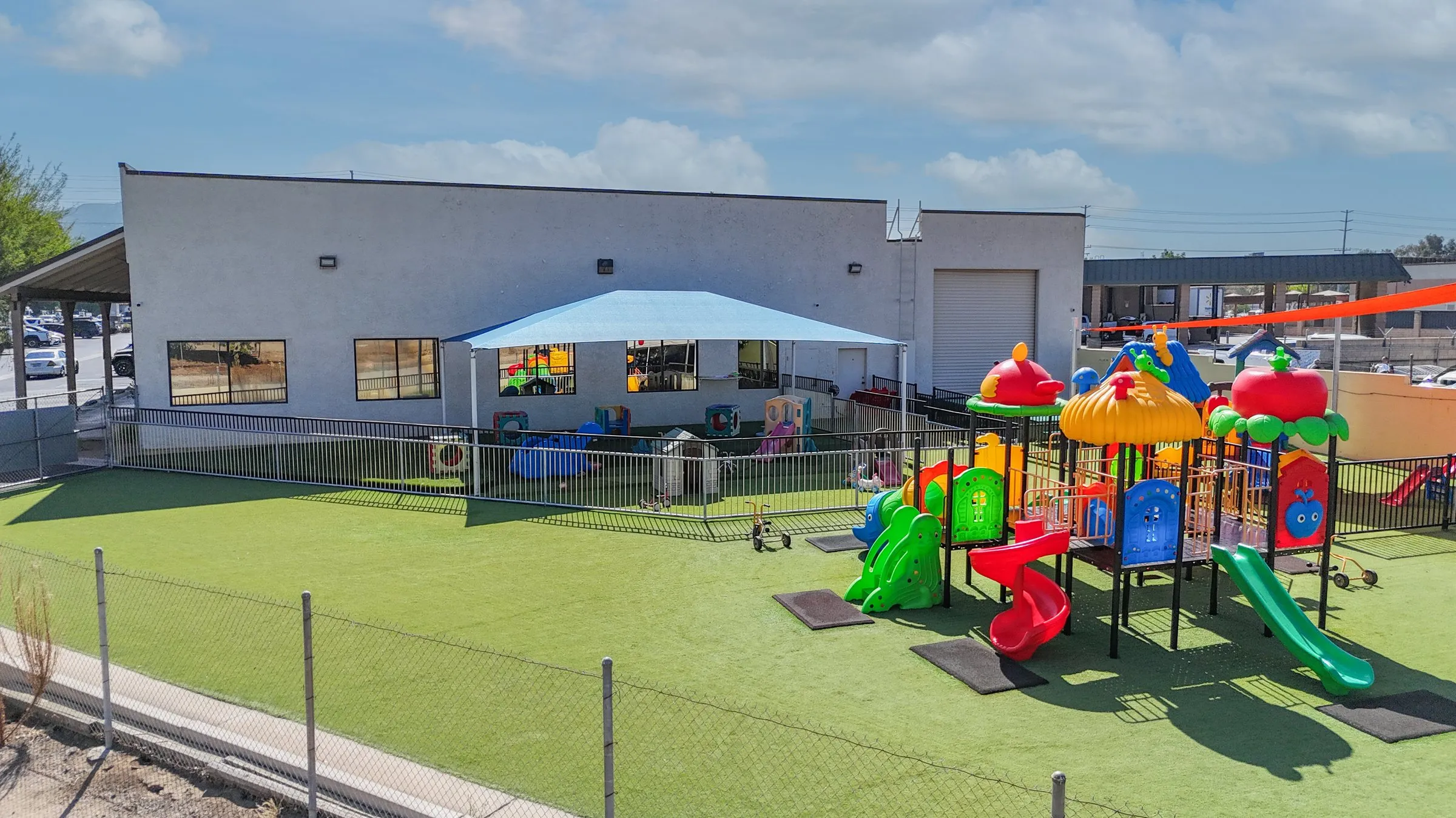 The Norco Montessori Academy building and its fenced turf playground with a shade canopy.