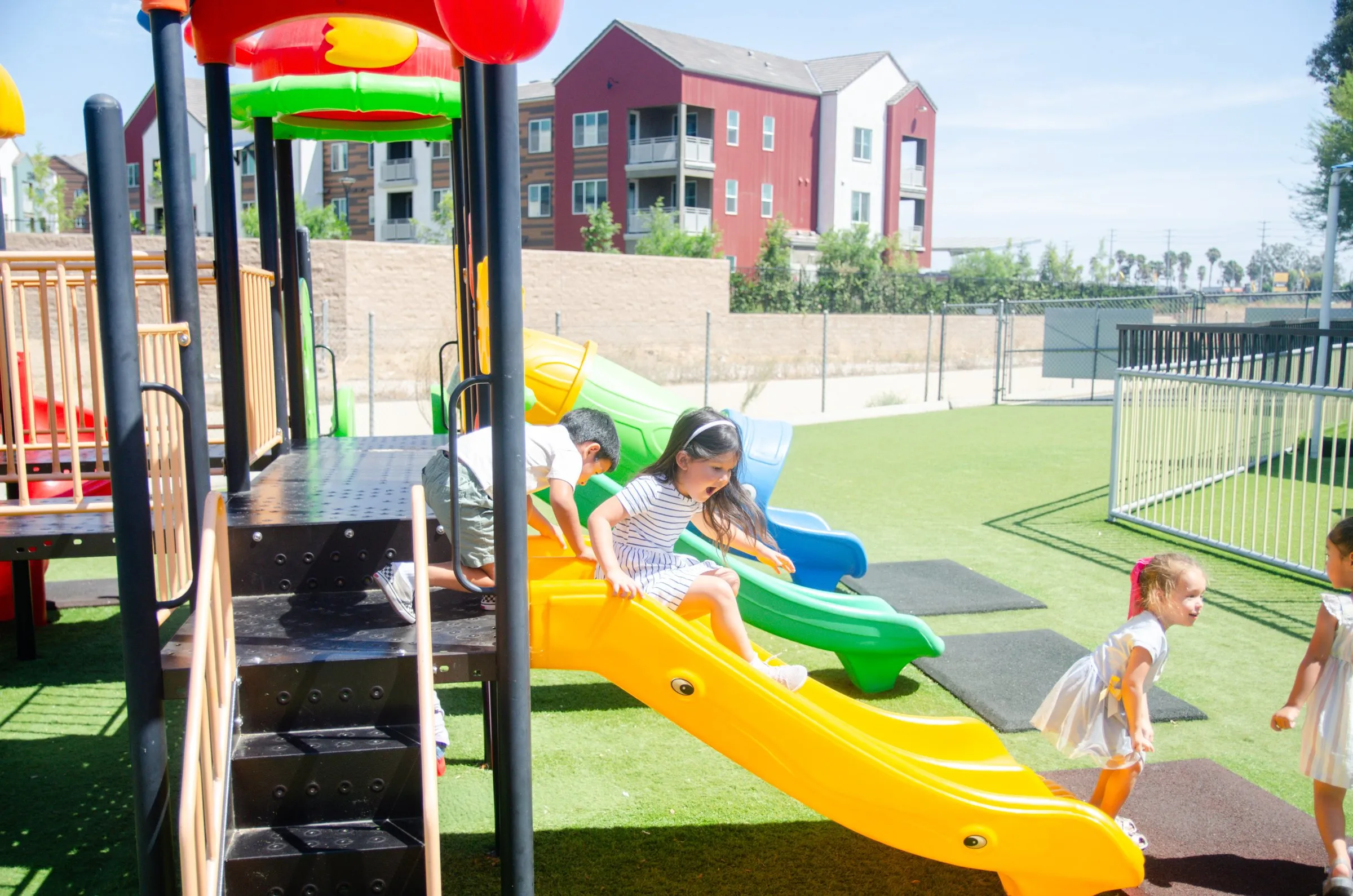 Children take turns on the slides of the playground on a sunny day.