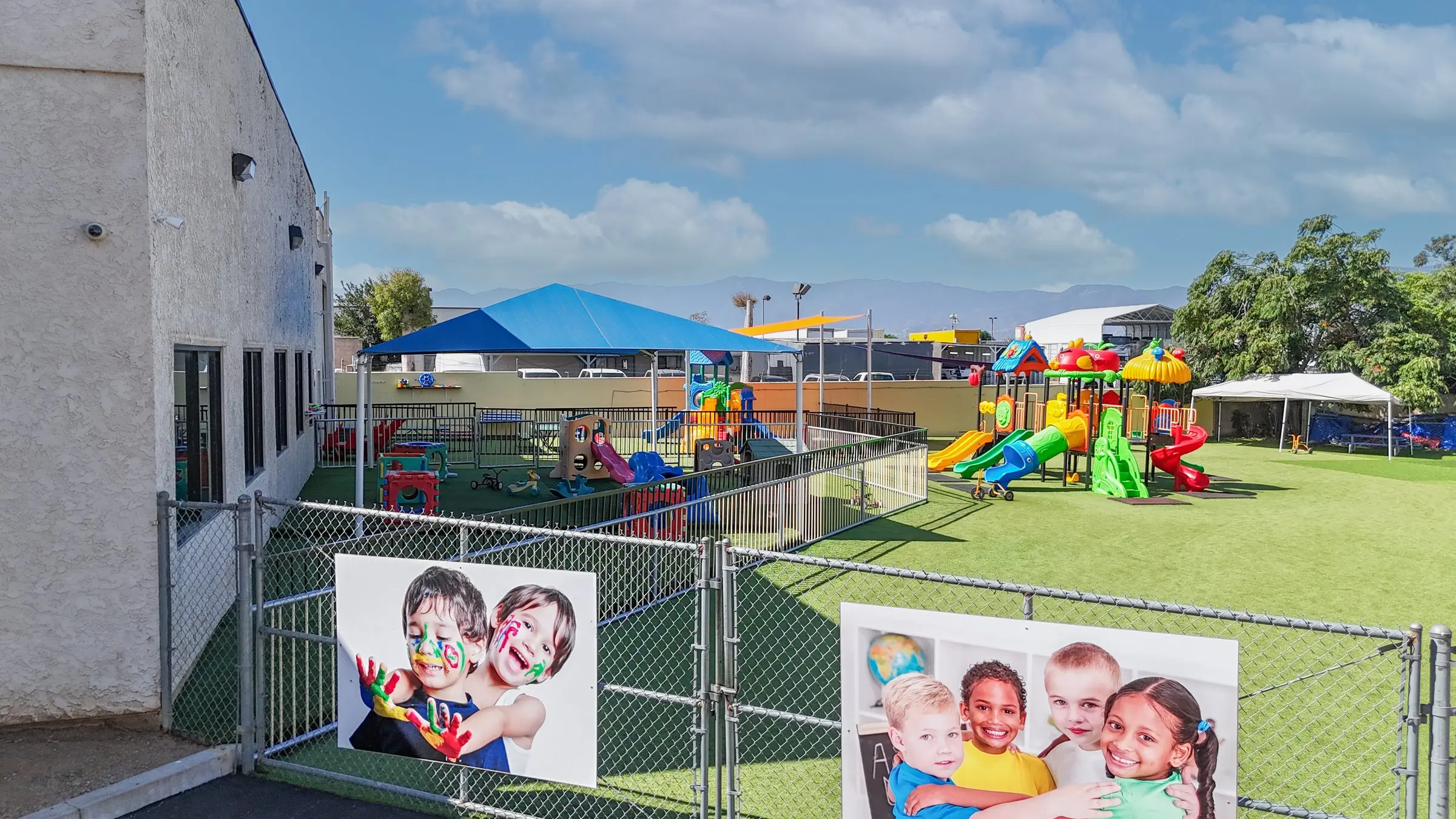 The fenced outdoor play yard with a blue shade canopy and a second play structure.